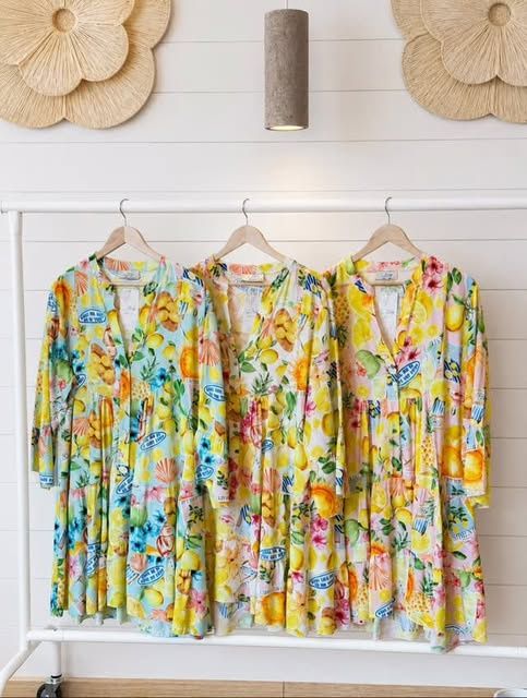 Lemon-print summer dresses hanging on a white shiplap wall
